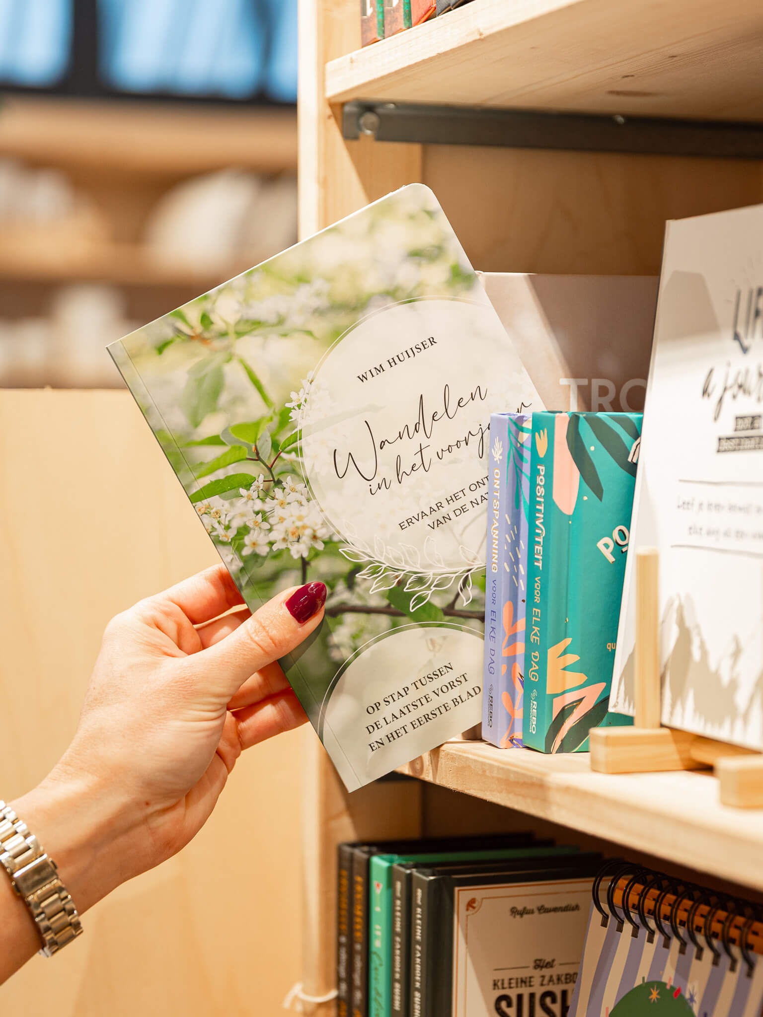 Een hand pakt een inspirerend boek uit een schap met boeken en cadeauartikelen in de winkel van Makers en Merken in Nijmegen en Bemmel.