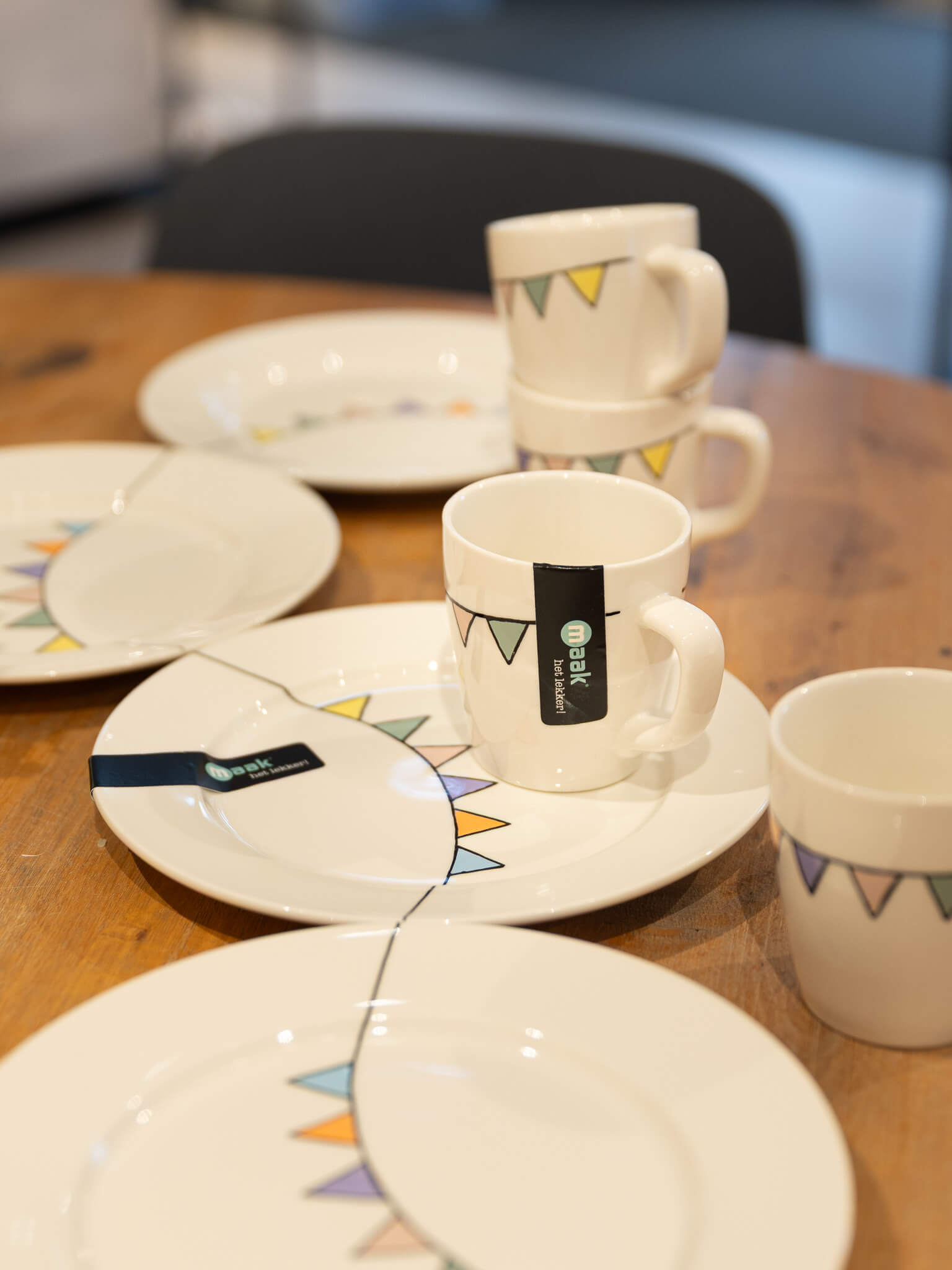 Borden en mokken uit de MAAK-collectie staan uitgestald op een houten tafel in de winkel van Makers en Merken.