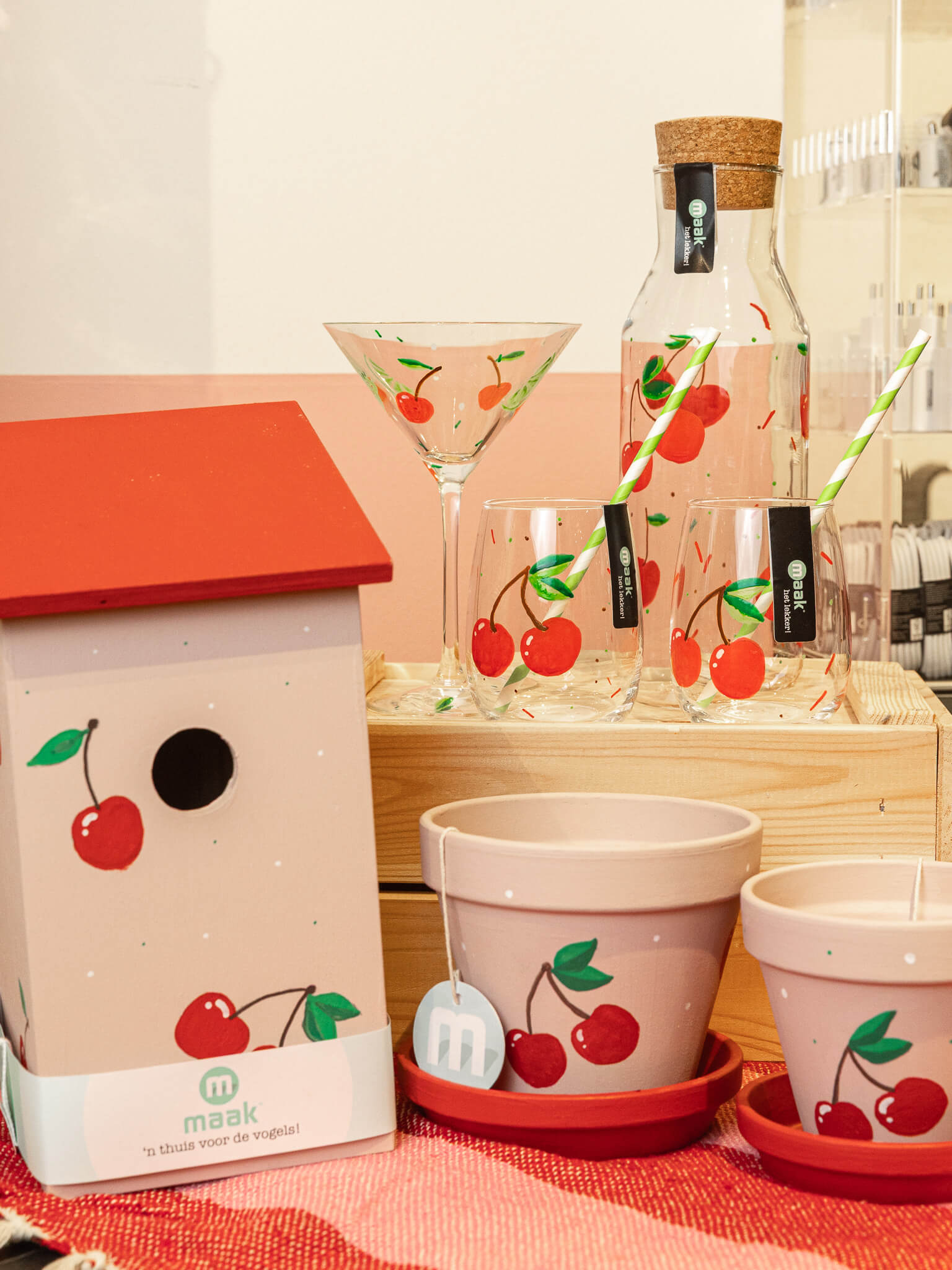 Handgemaakte woonaccessoires van MAAK bij Makers & Merken Nijmegen Een vrolijke collectie met beschilderde glazen, bloempotten en een vogelhuisje met kersenmotief, gemaakt door de makers en verkocht bij Makers & Merken Nijmegen.